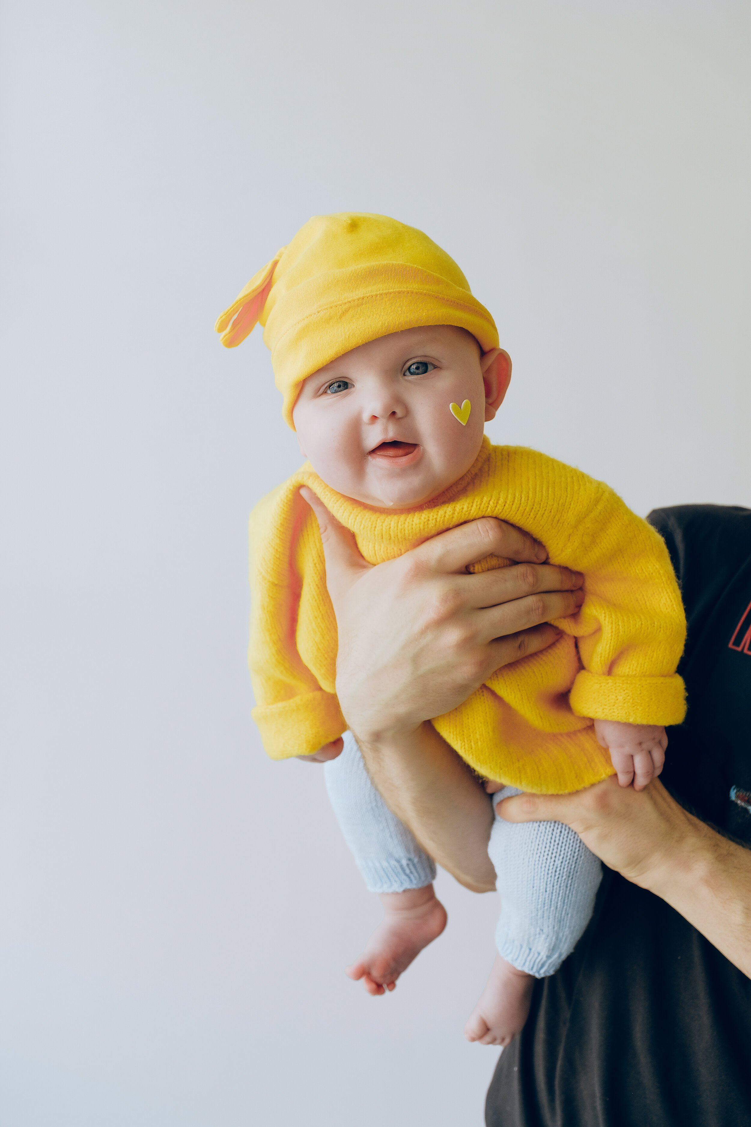 crop-parent-holding-smiling-baby-in-arms-against-gray-wall-3845495.jpg