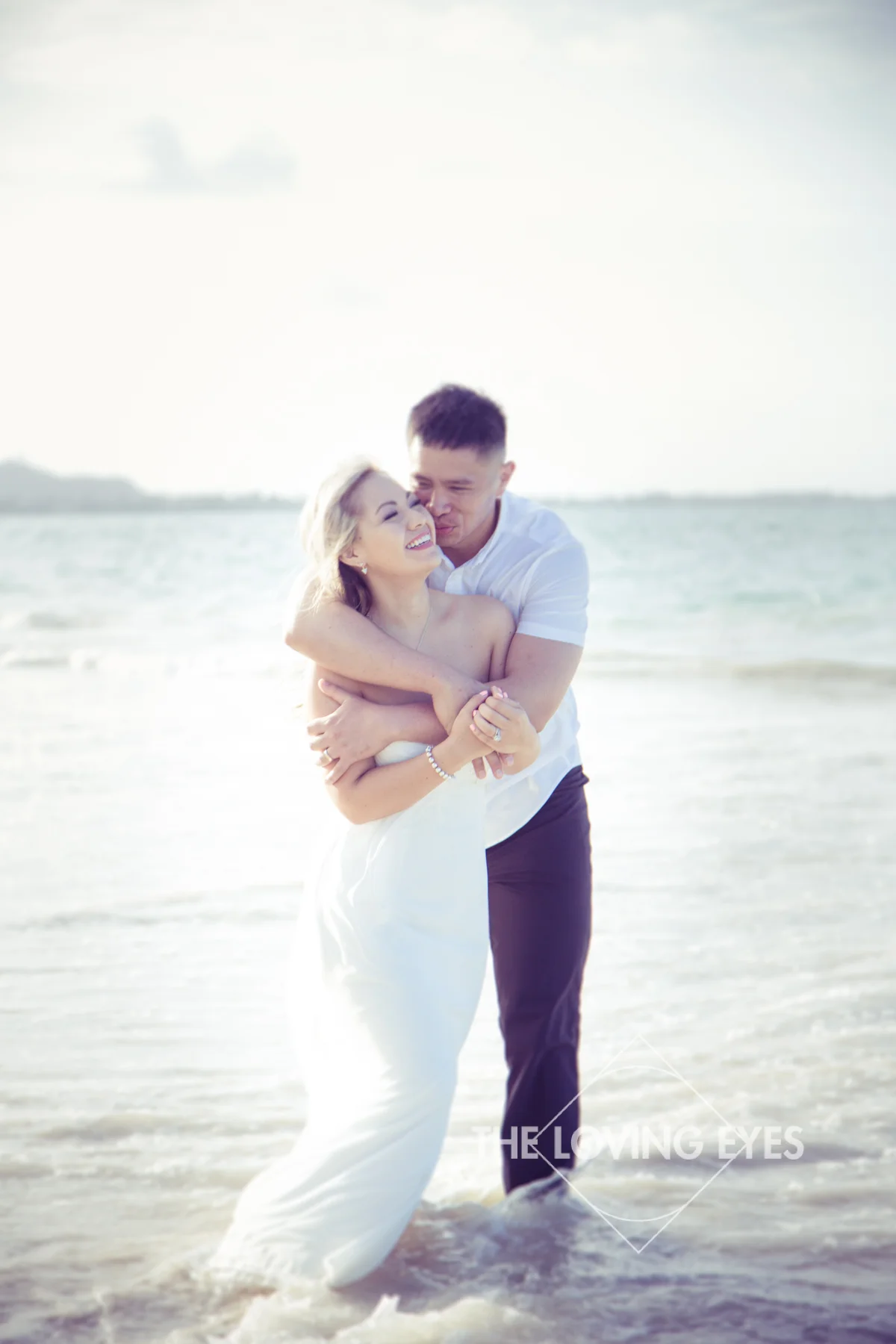 Couple hugging and playing on the beach during Hawaii engagement photography at Kailua Beach