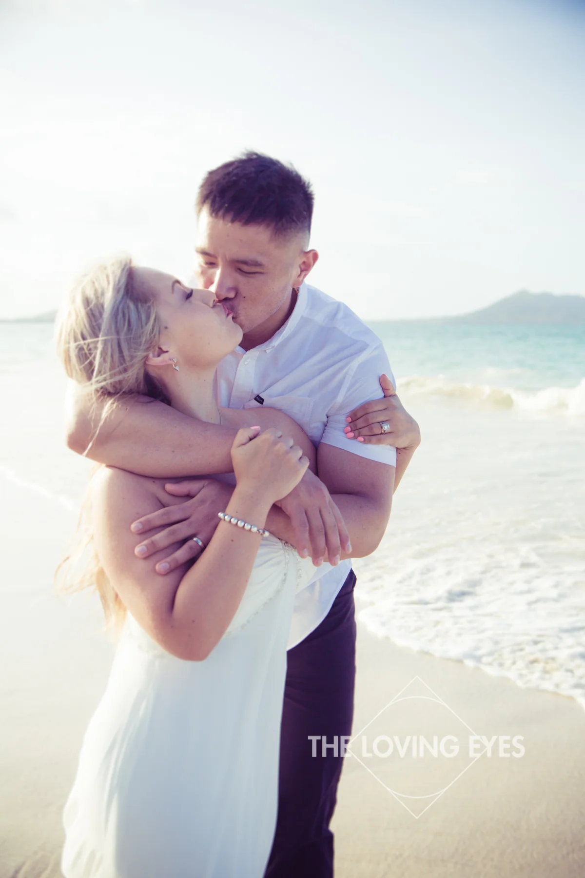 Couple hugging and playing on the beach during Hawaii engagement photography at Kailua Beach
