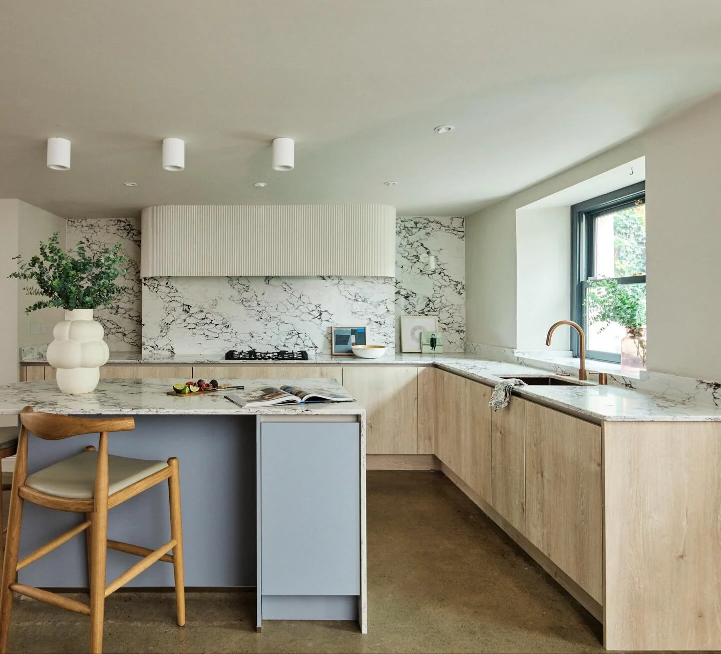 The design brief for this Portobello kitchen focused on elevating the mood through strategic material and colour choices. 
We opted for an oak and light blue palette that complements the stone's veining, while a custom fluted canopy adds texture.
Kit