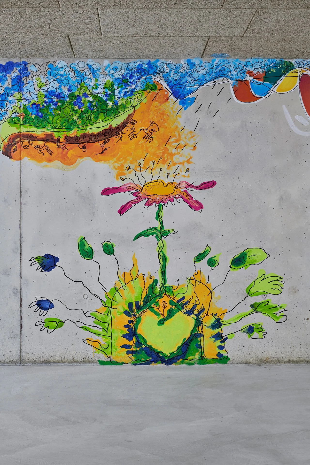 Colorful mural on a gray concrete wall shows a tall pink flower rising from a vivid green-and-yellow garden, beneath a band of blue blossoms and warm orange clouds; playful, hopeful tone.