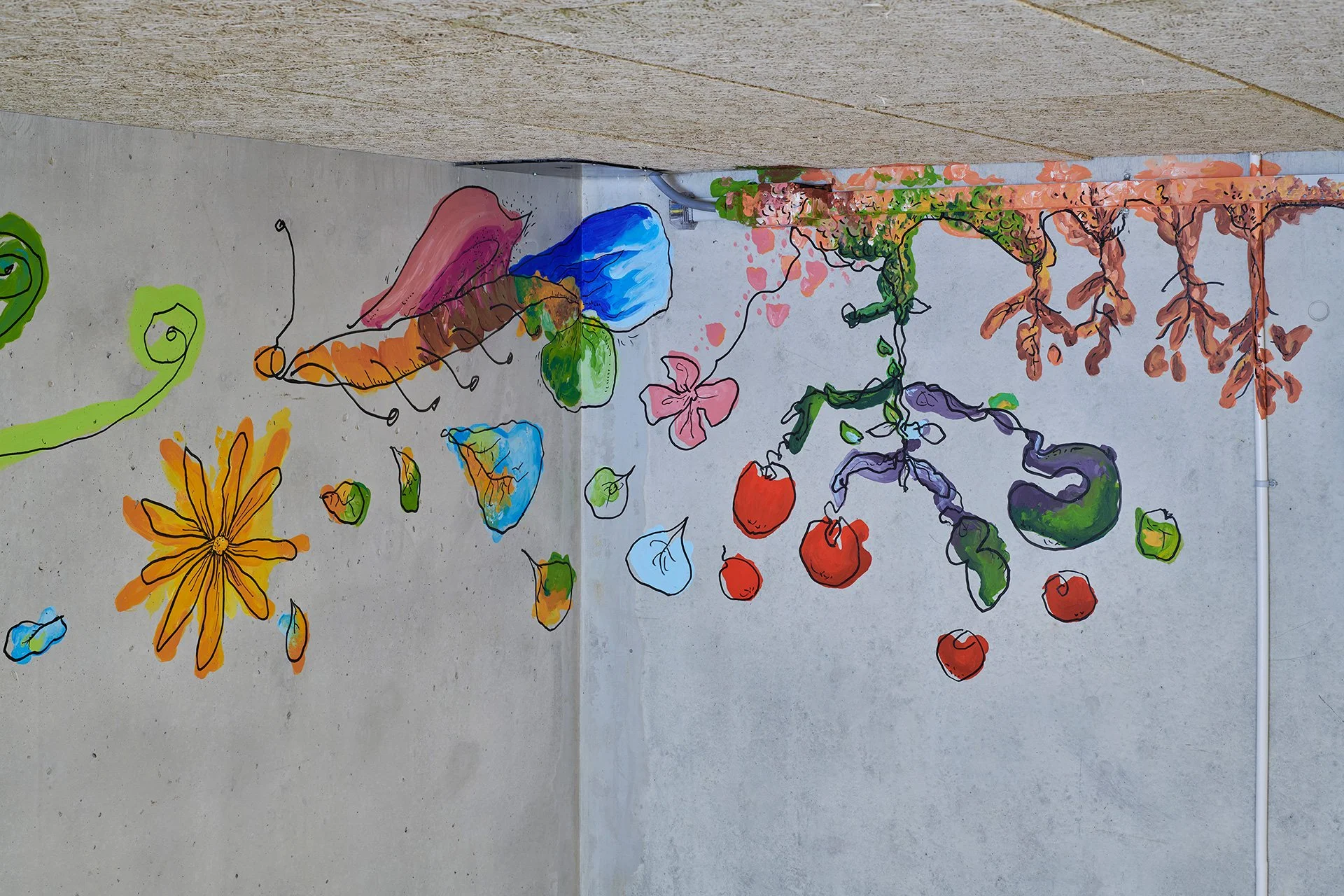 Colorful childlike mural of imaginary plants and vegetables, including a bright orange flower, green vines, red tomatoes, purple eggplant, and dangling roots on a gray wall; playful, whimsical tone.