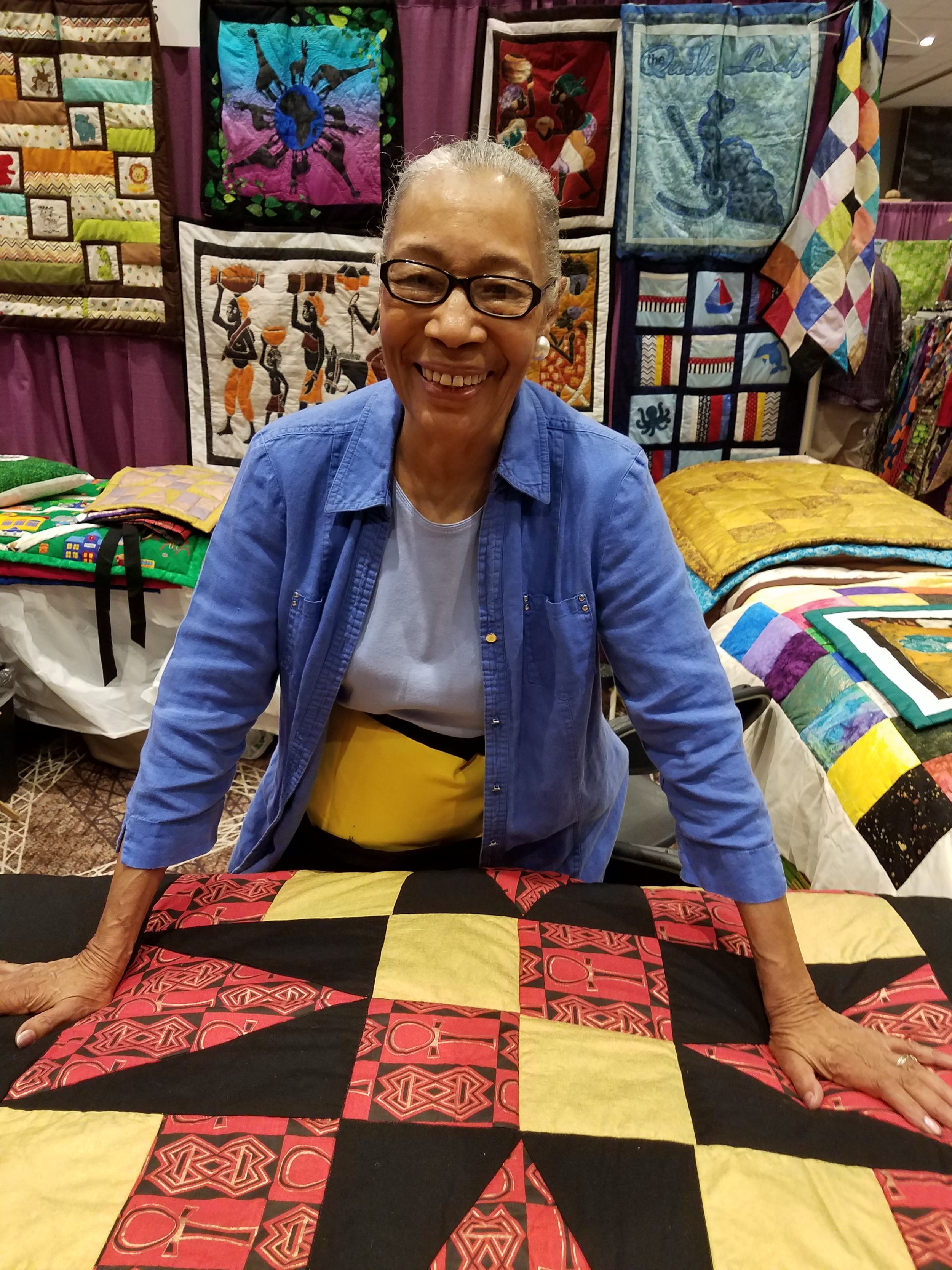 quilt artist Loretta Craig, displaying several colorful quilts