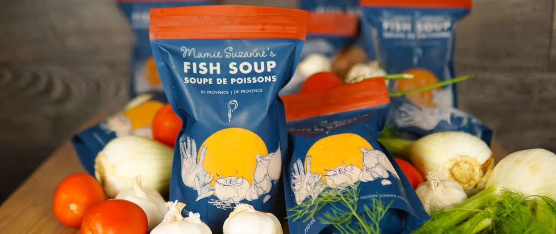 Close-up of Mamie Suzanne’s Fish Soup packaging designed by Laurelle Armet, surrounded by fresh ingredients that inspired the illustration and Provençal color palette.