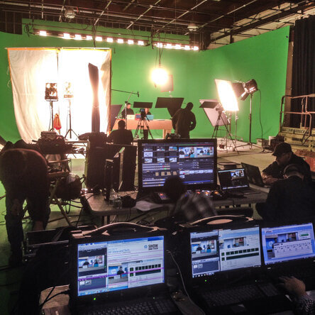 Television production studio with green screen, lighting, cameras, and crew operating equipment
