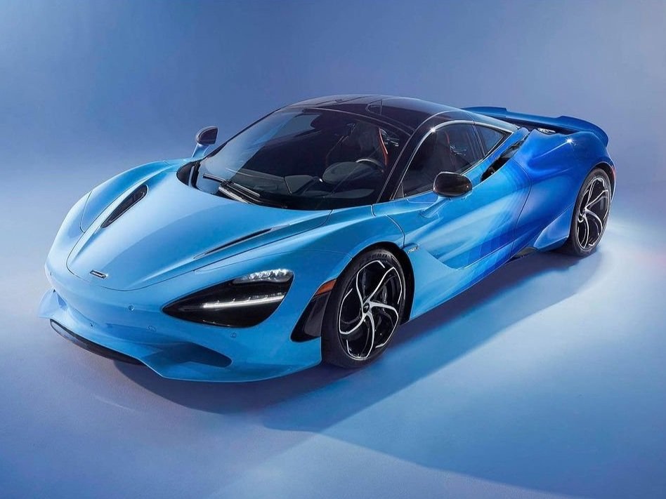 A sleek, blue sports car with a black roof and distinctive black alloy wheels, positioned on a blue background.