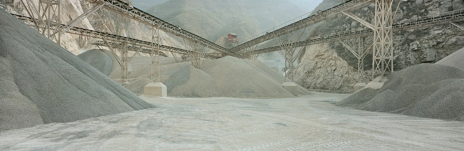 Quarry and temple. Bayin, Gansu, China, 2011. A private temple set above a quarry. Quarries producing limestone, used for construction and as flux for the process of steel making, are among a number of common features found in industrial towns. Mining industries set up near mountains that provide coal and other valuable mineral deposits. Coal-fired power stations are located in the same area and steel plants that need energy also locate near the power stations. Coking plants are located nearby to convert coal into coke, which is also necessary for steel production. 