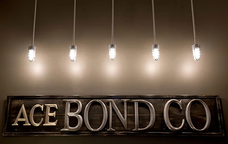  5 industrial ceiling lights illuminating an&nbsp;8' custom&nbsp;sign. 