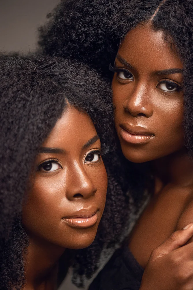 A portrait of African American twins with natural hair textures shot in studio.