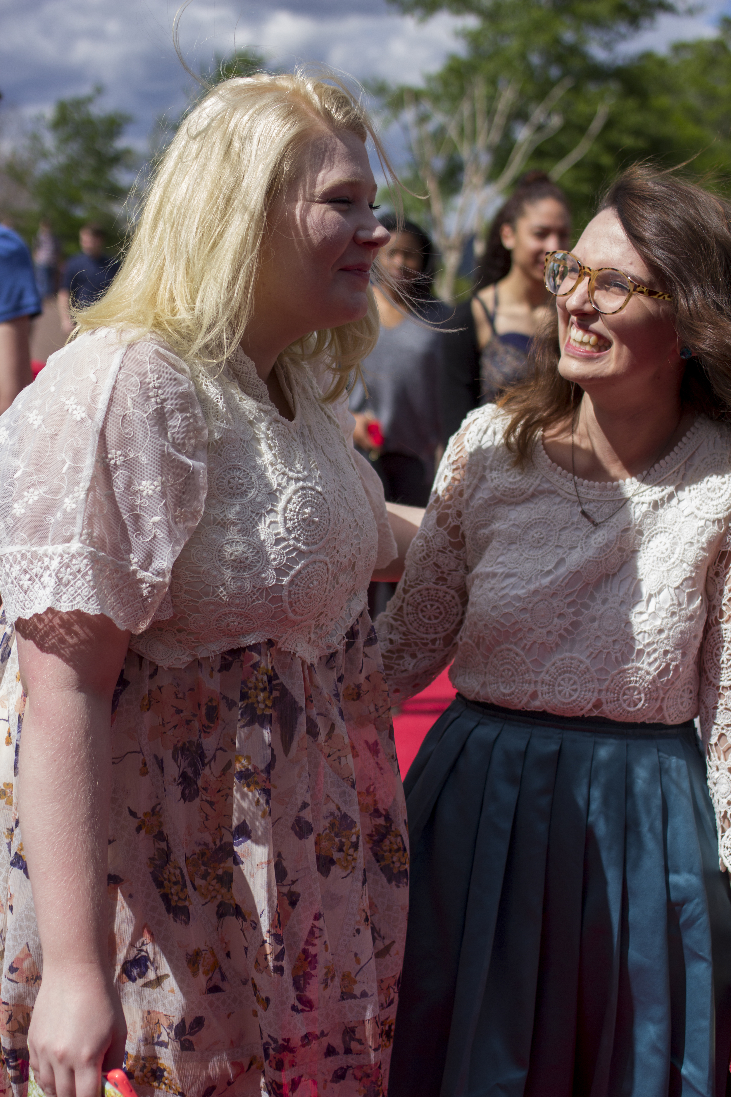 Rather than getting flustered, Victoria Pujdak and Emily Artus laugh at the high gusts of wind getting in the way of them getting a picture together wearing their matching styled dresses.