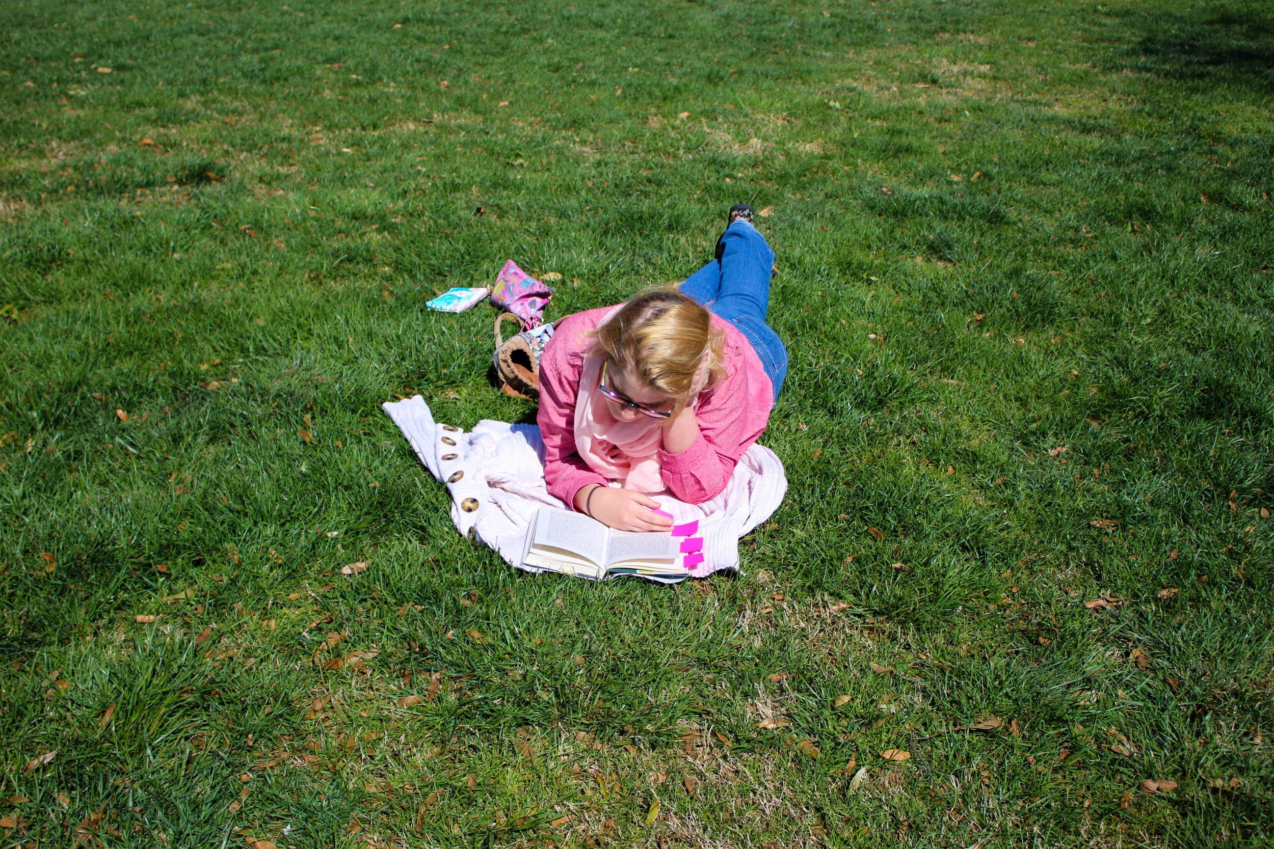 Linnea Stevens, a studio art major, enjoys the pleasant weather as she lays on the grass while reading.
