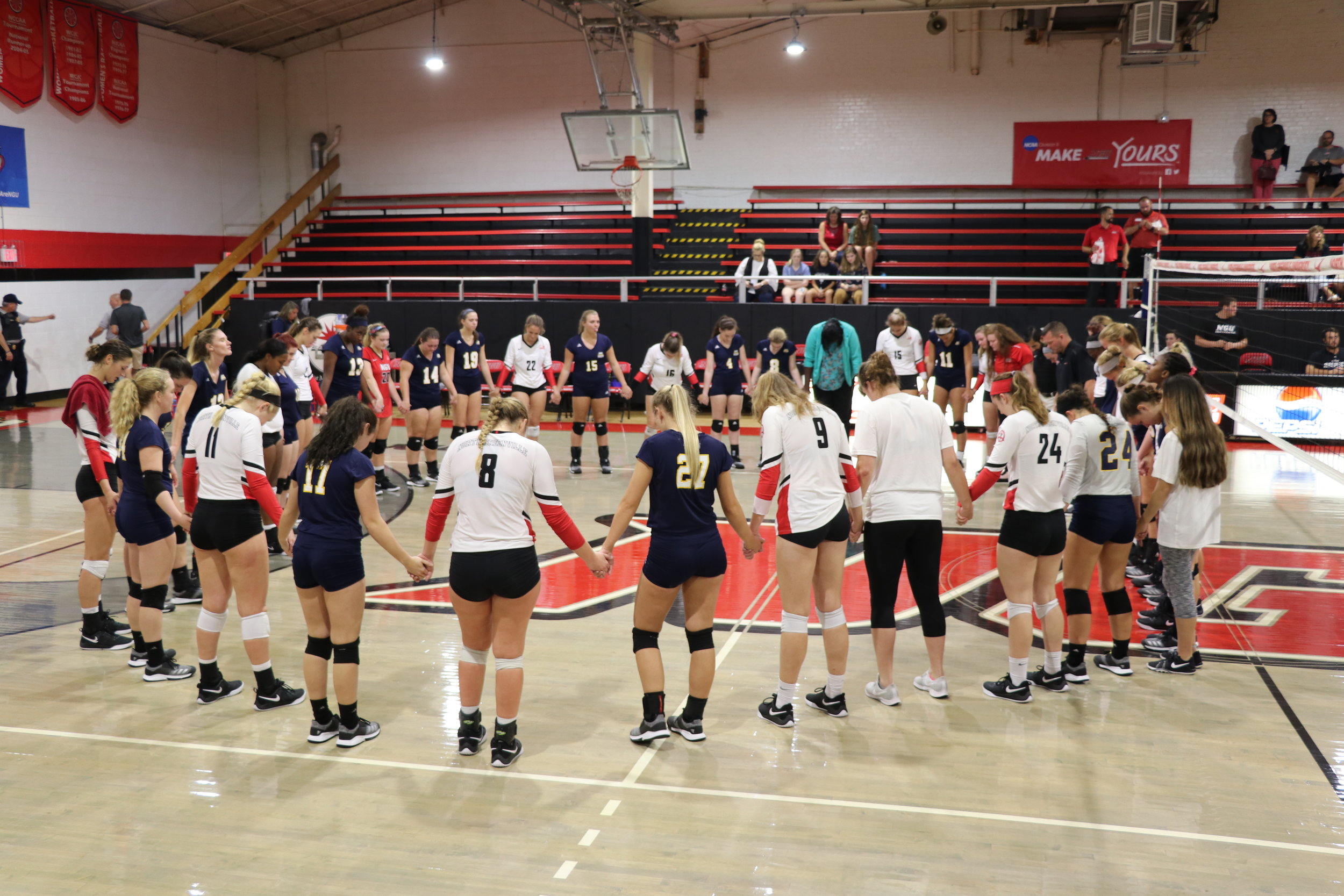 The two teams join hands and pray together after the game.