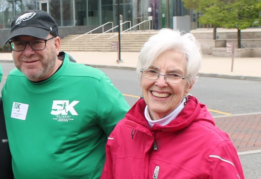 Woman with red jacket and white hair, man with green shirt and black hat