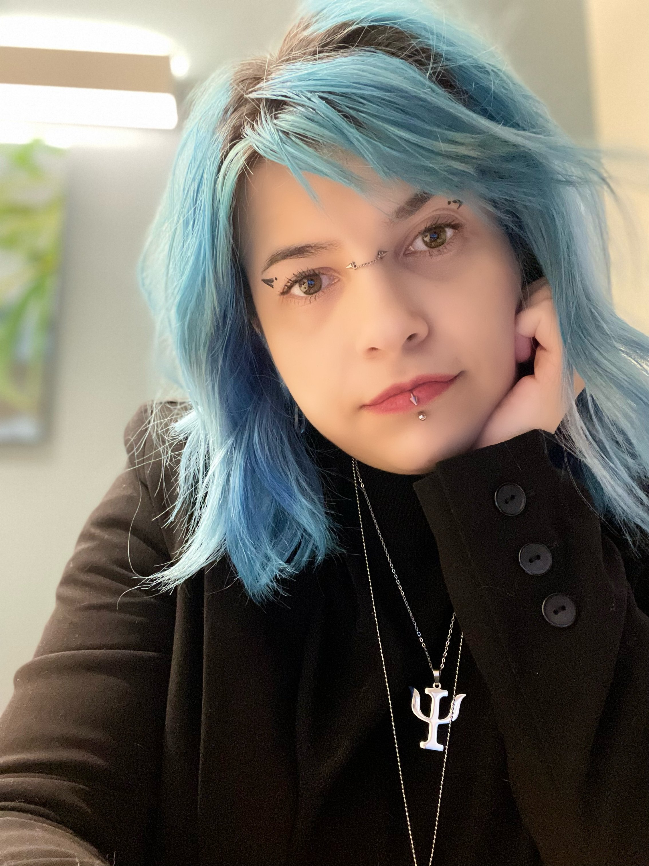 professional headshot of young woman with blue hair and facial piercings Sara Zulghena