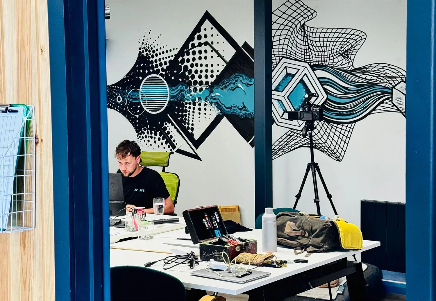 A view into an office space with an employee working with a large scale mural behind them