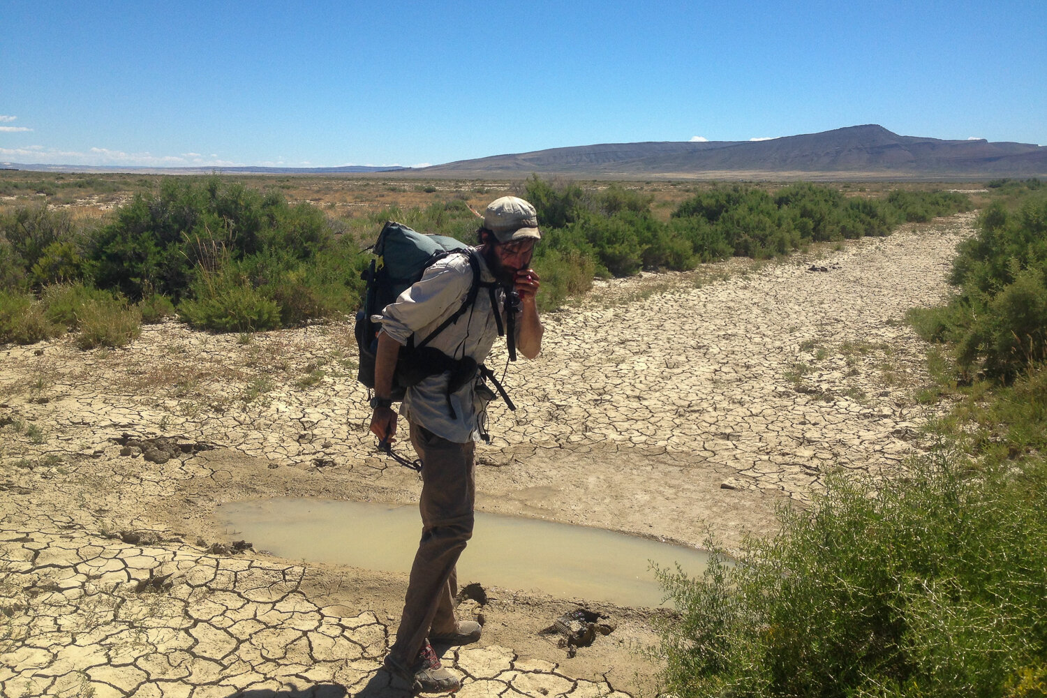 Using some water from a muddy rut to cool off to avoid heat exhaustion in the desert