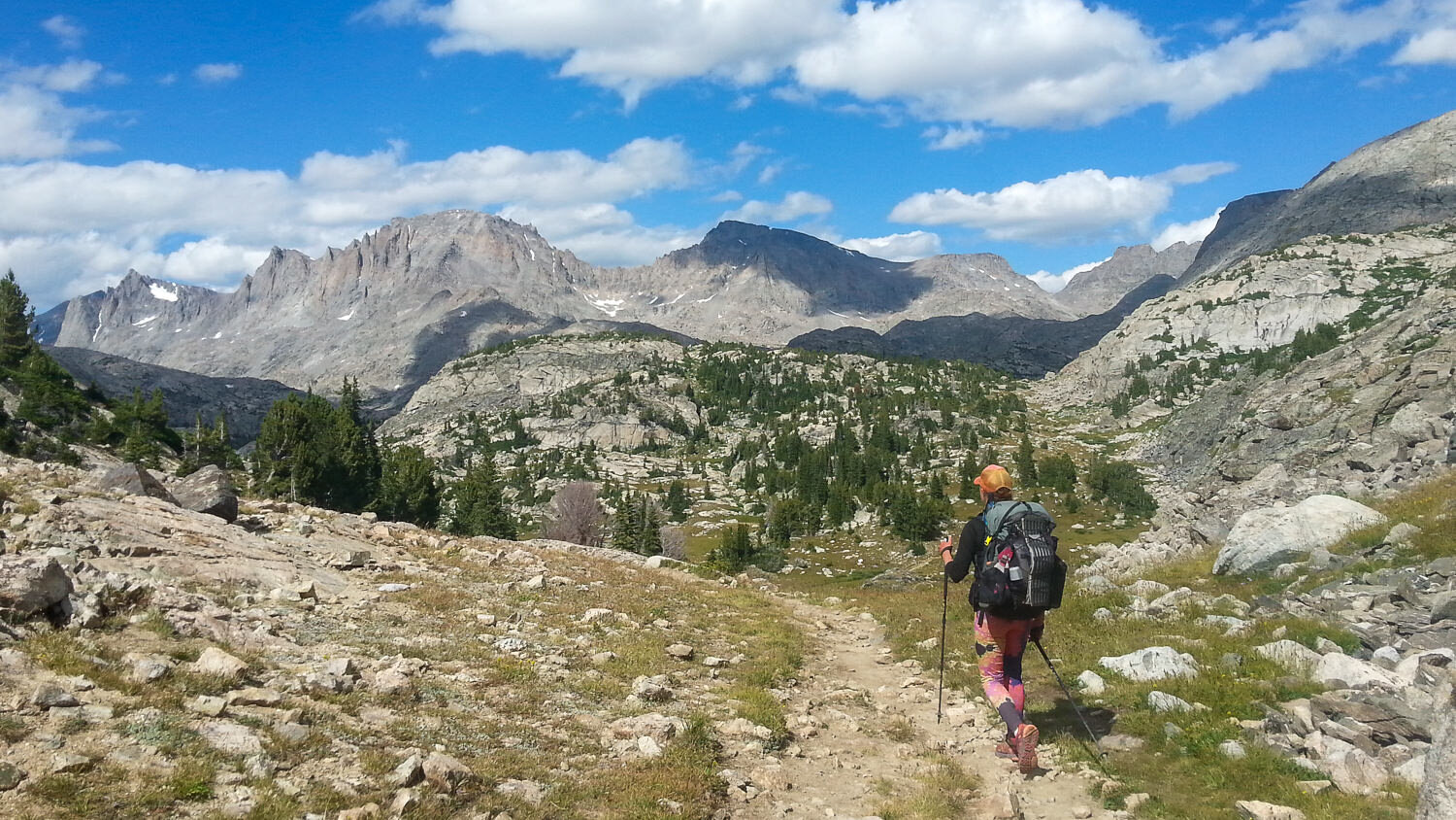 A backpacker hiking in the Wind River Range in Wyoming with distant mountains in the background