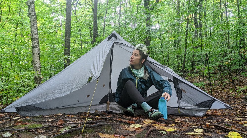 A hiker sitting in the door of the Six Moon Designs Lunar Solo tent