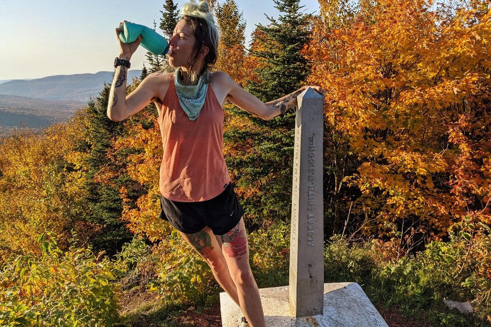 A hiker standing on the Long Trail northern terminus monument