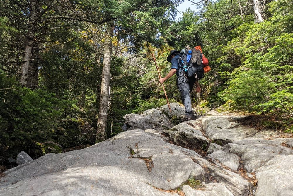 A Long Trail hiker climbing up some steep rocks