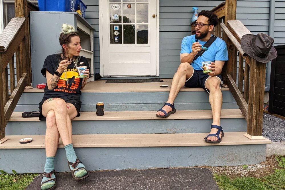 Two Long Trail hikers sitting on the steps of a hostel eating ice cream