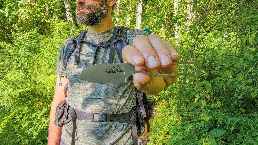 A backpacker holding the ULA Alpha Knife