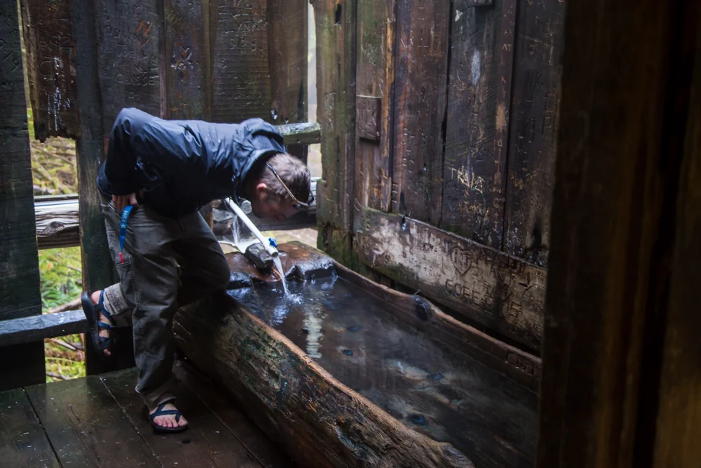 Me inspecting one of the hollowed out tree bathtubs. We scrubbed the tub before and after our soak, so as to bathe cleanly and leave a tub ready for the next folks.