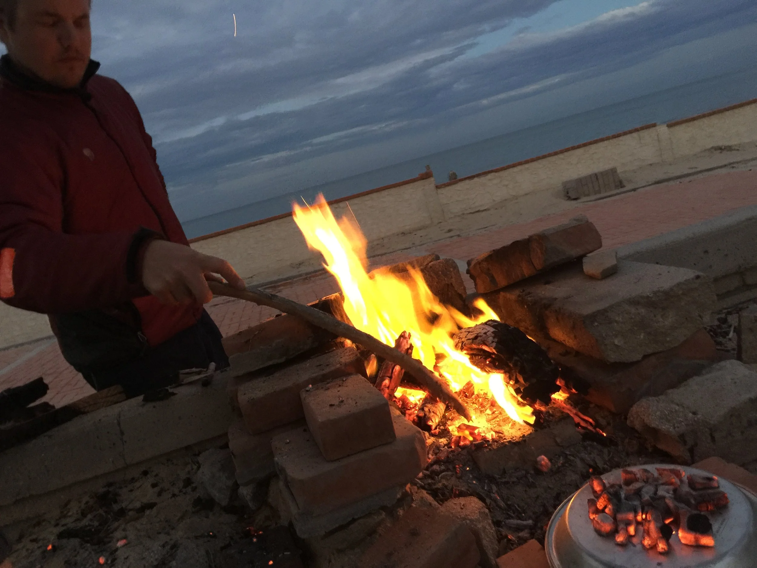 Free fuel, collected from the beach. The dish in the foreground is a pie plate heaped with coals, acting as a dutch oven to bake the corn bread within.