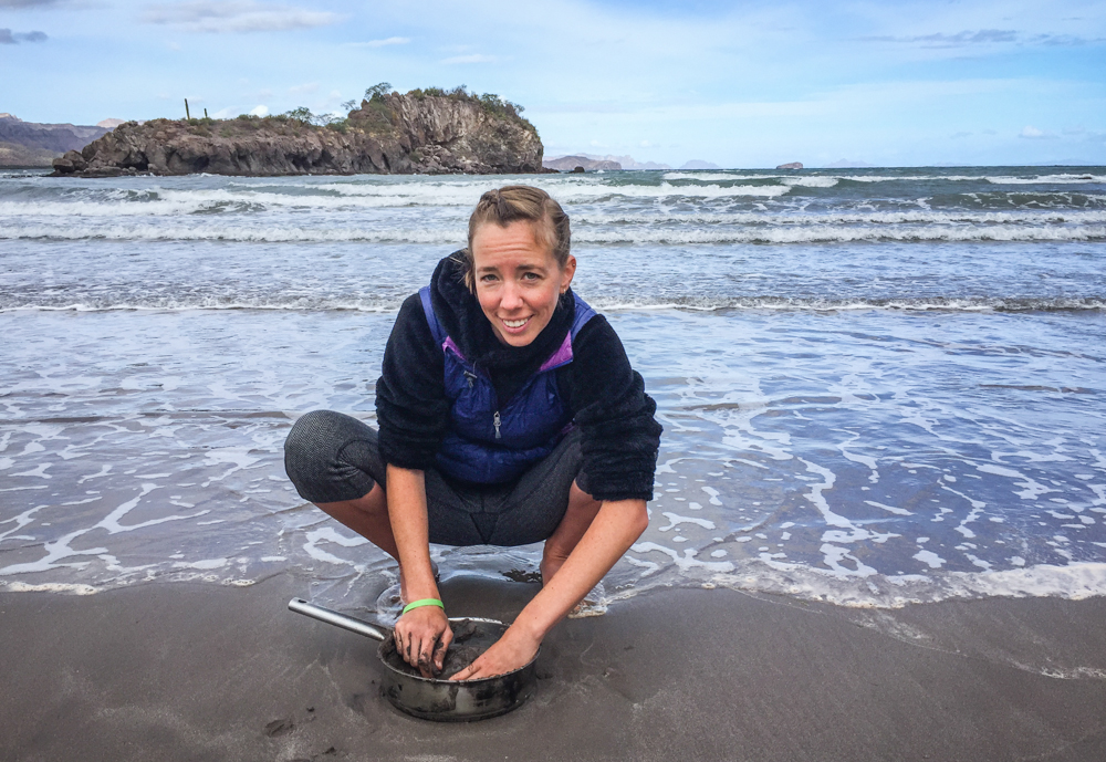 Chels, usually the photographer, cleaning dishes in the sea (or maybe making mud pies?)