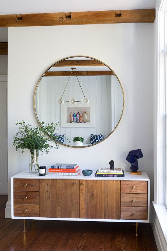 The mirror above this custom walnut sideboard reflects the Apparatus Studio Trapeze light fixture, featured in the breakfast nook. Above the sunroom (photo, left) hang three Moooi Random pendant lights. Varying sizes and staggering heights compliment the linearity of the exposed beam ceiling.