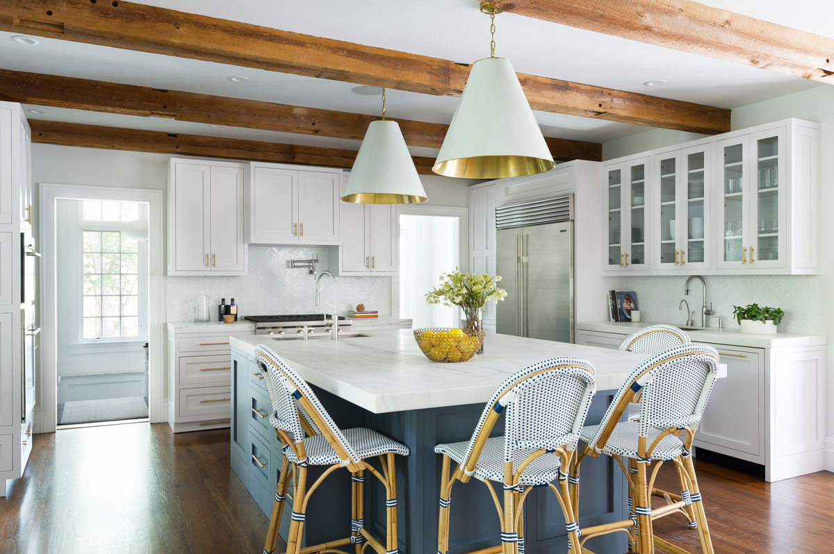 The kitchen takes a traditional “Hamptons White Kitchen” concept and modernizes it with a deep blue island, herringbone mother-of-pearl backsplash and brass details thoughtfully scattered throughout the space. The sturdy, stain-proof Serena and Lily barstools make this a place for the entire family to enjoy.
