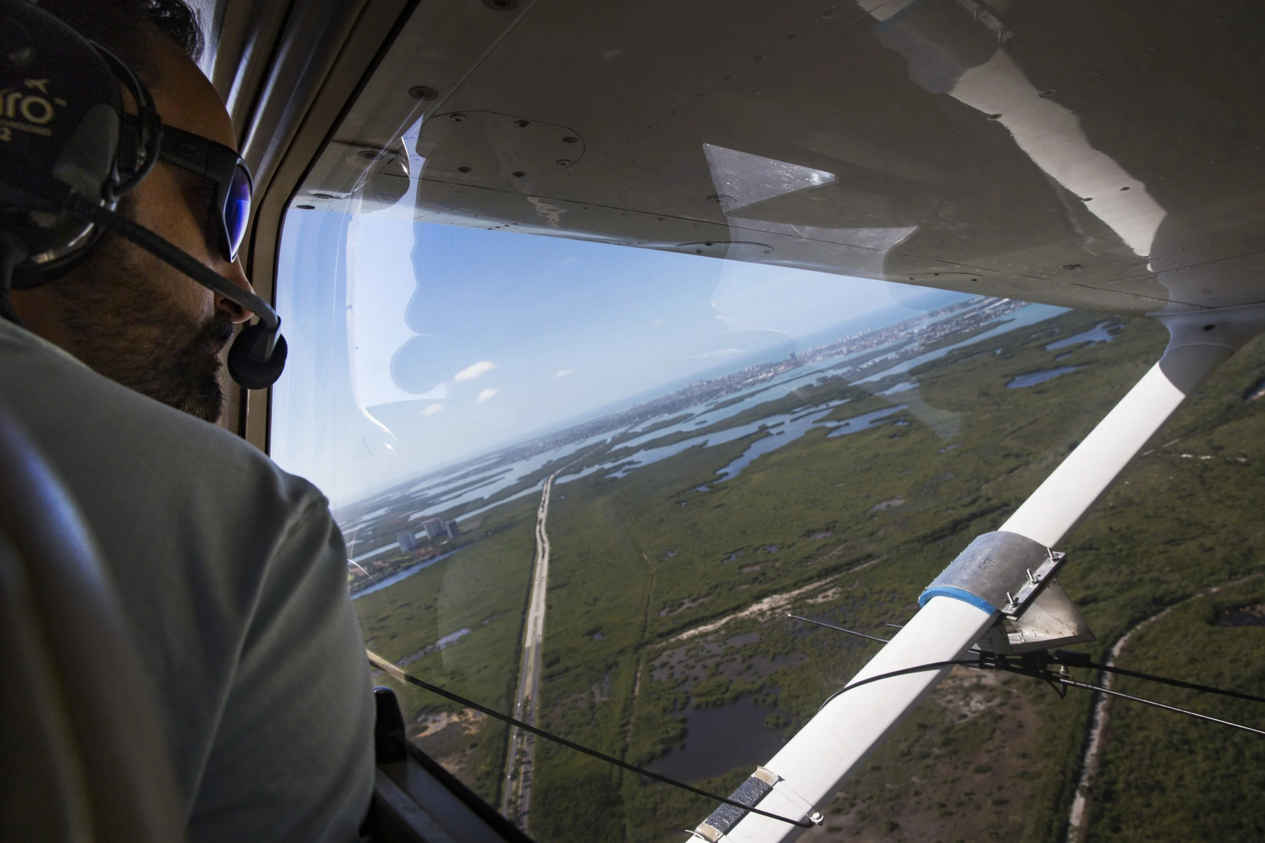  Ian Bartoszek, 40, a science coordinator and wildlife biologist with the Conservancy of Southwest Florida, looks out the window of a plane while tracking Burmese pythons in Collier County using radio telemetry on Monday, March 27, 2017. Male snakes 