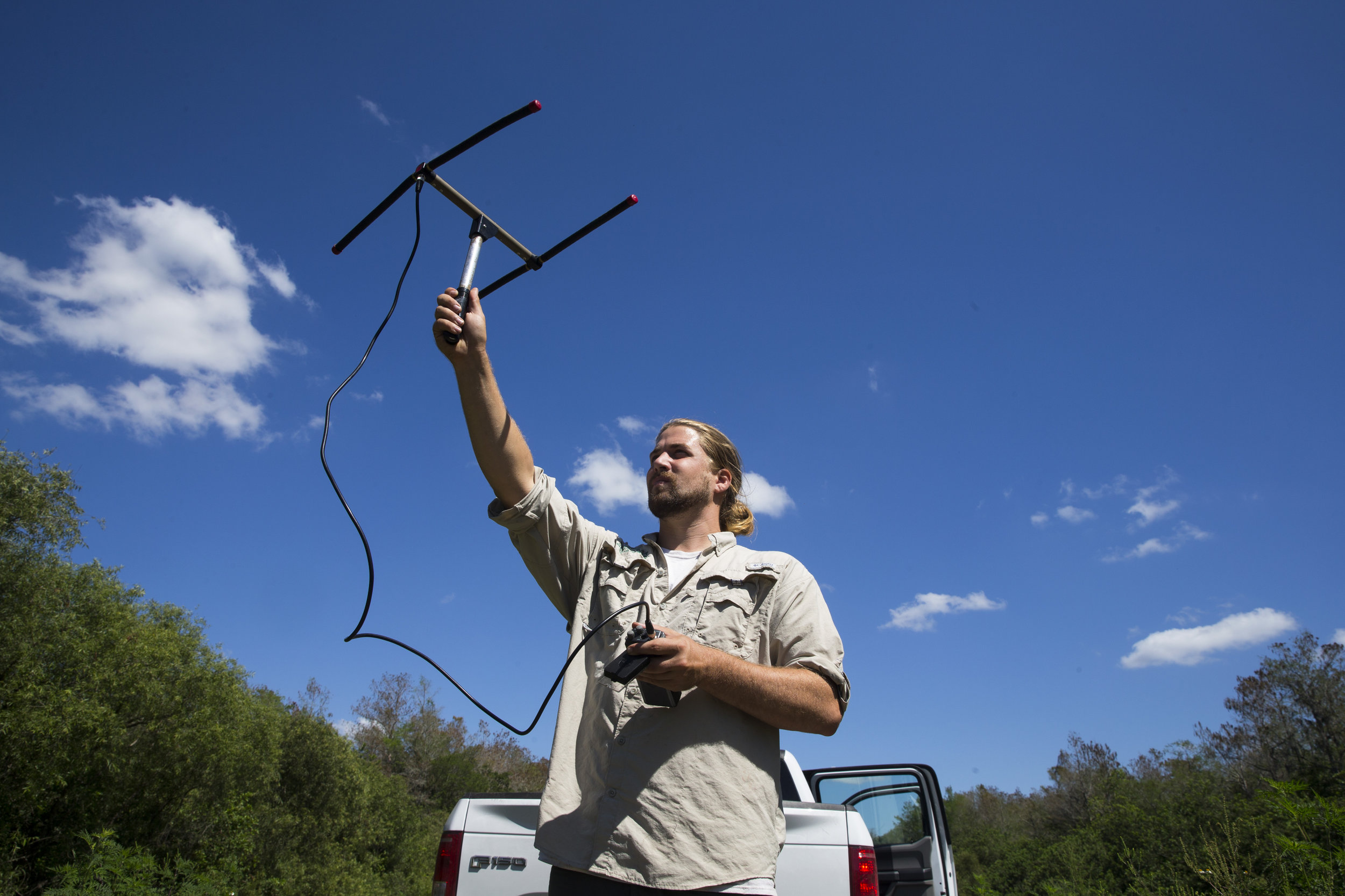  Ian Easterling, 25, a conservation associate with the Conservancy of Southwest Florida, raises an antenna to monitor Burmese pythons through radio telemetry along the edge of urban Collier Country on Tuesday, March 28, 2017.&nbsp; 