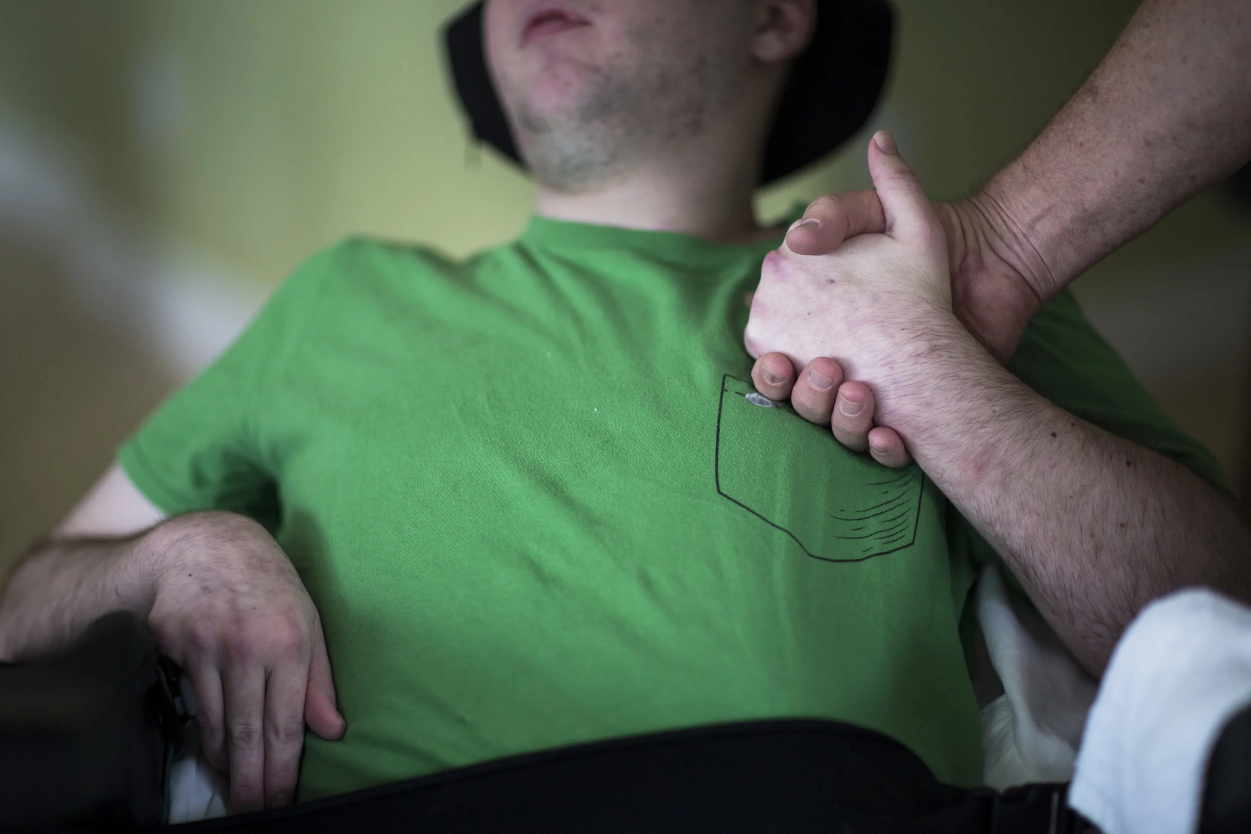  Mitchell Reidy, 19, holds his dad's hand while sitting at home in Naples on Wednesday, Nov. 8, 2017.&nbsp;Reidy, who suffered a traumatic brain injury in Feb. 2017, was forced to return home after insurance rules lead to his discharge this past Mond