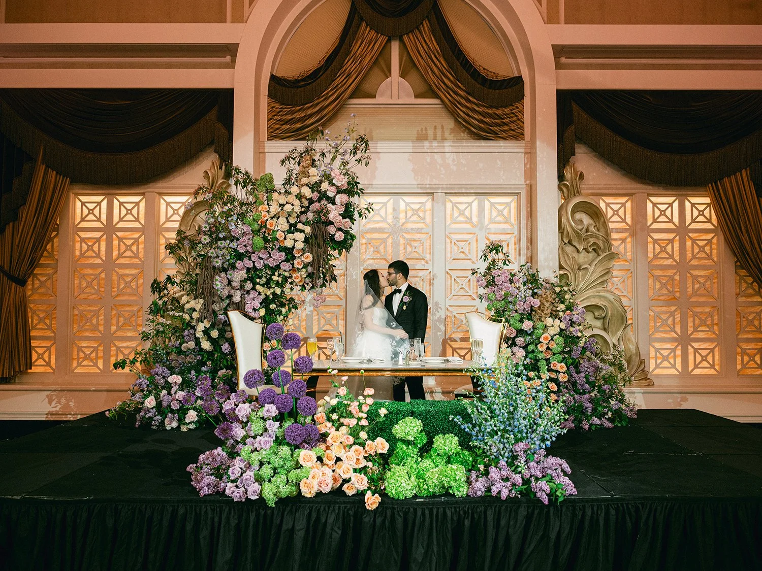  A grand and vibrant wedding portrait of Jenny and Shay sharing a joyful moment inside the luxurious ballroom of The Venetian in New Jersey. 