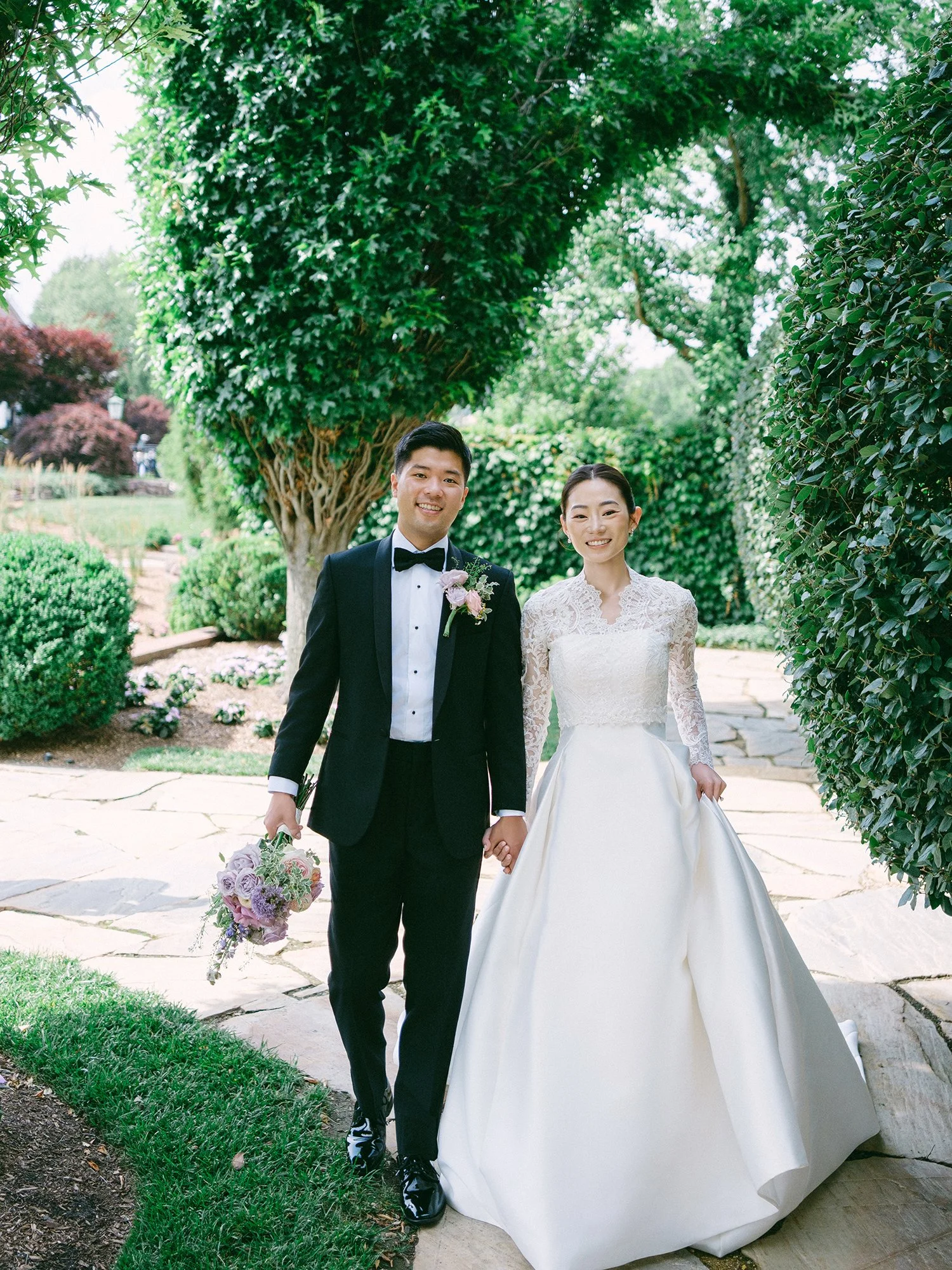 Wedding portrait of Amanda and Michael smiling in front of the historic mansion at Hamilton Farm Golf Club by Haseok Chung Studio.
