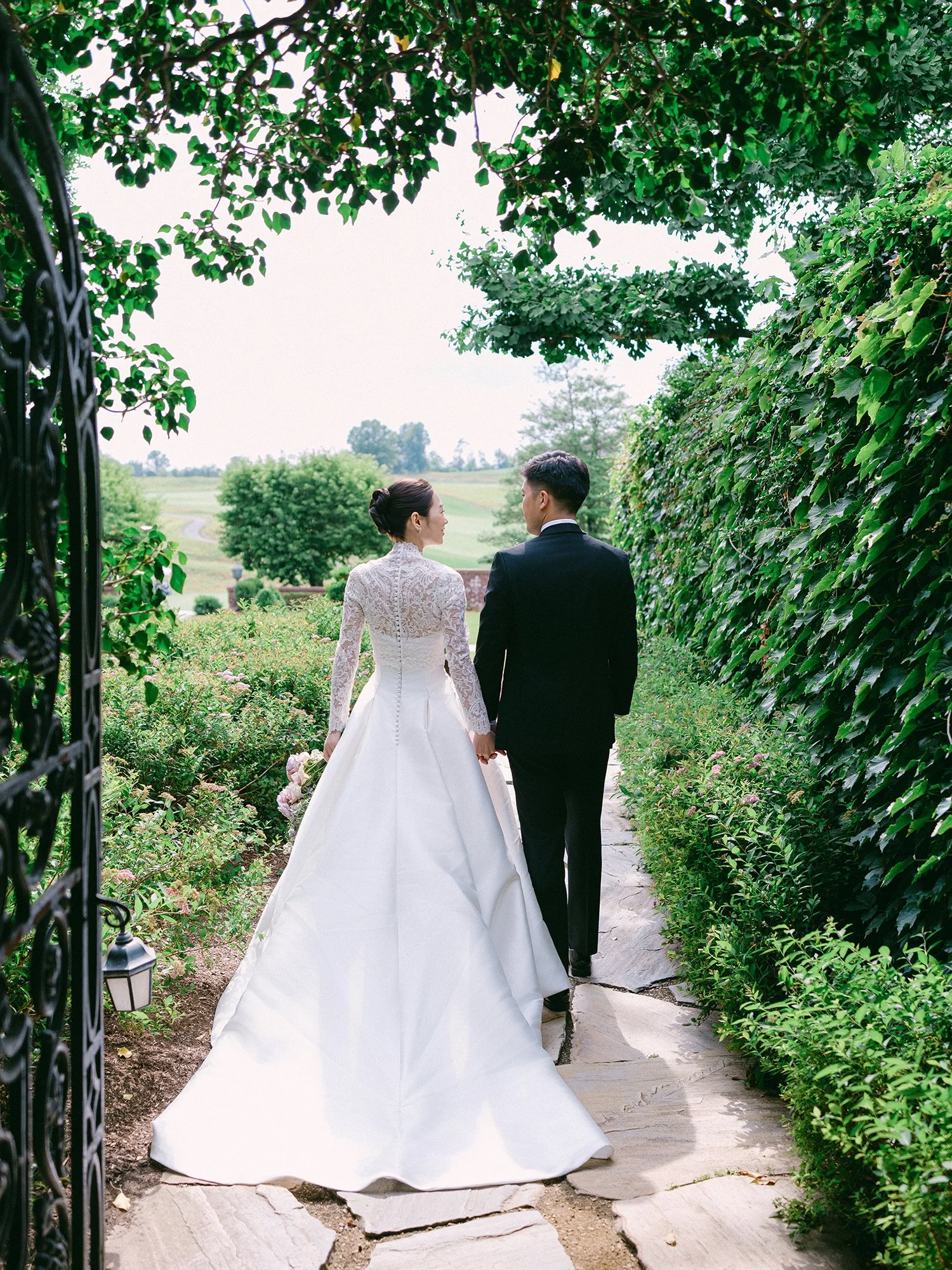 Wedding portrait of Amanda and Michael smiling in front of the historic mansion at Hamilton Farm Golf Club by Haseok Chung Studio.