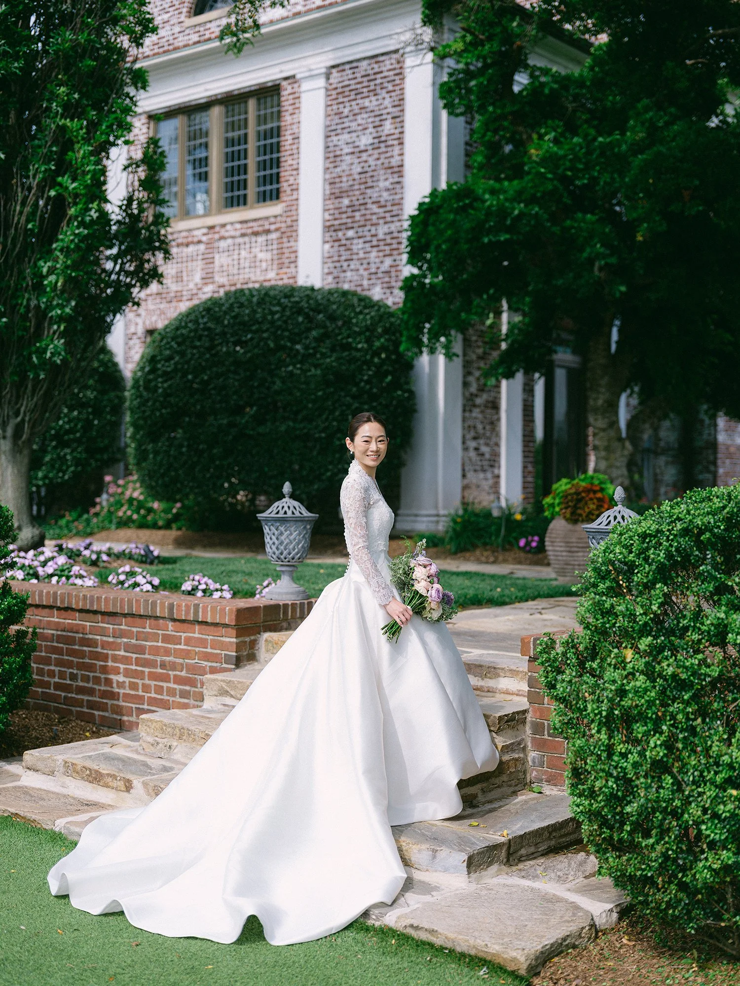Wedding portrait of Amanda and Michael smiling in front of the historic mansion at Hamilton Farm Golf Club by Haseok Chung Studio.