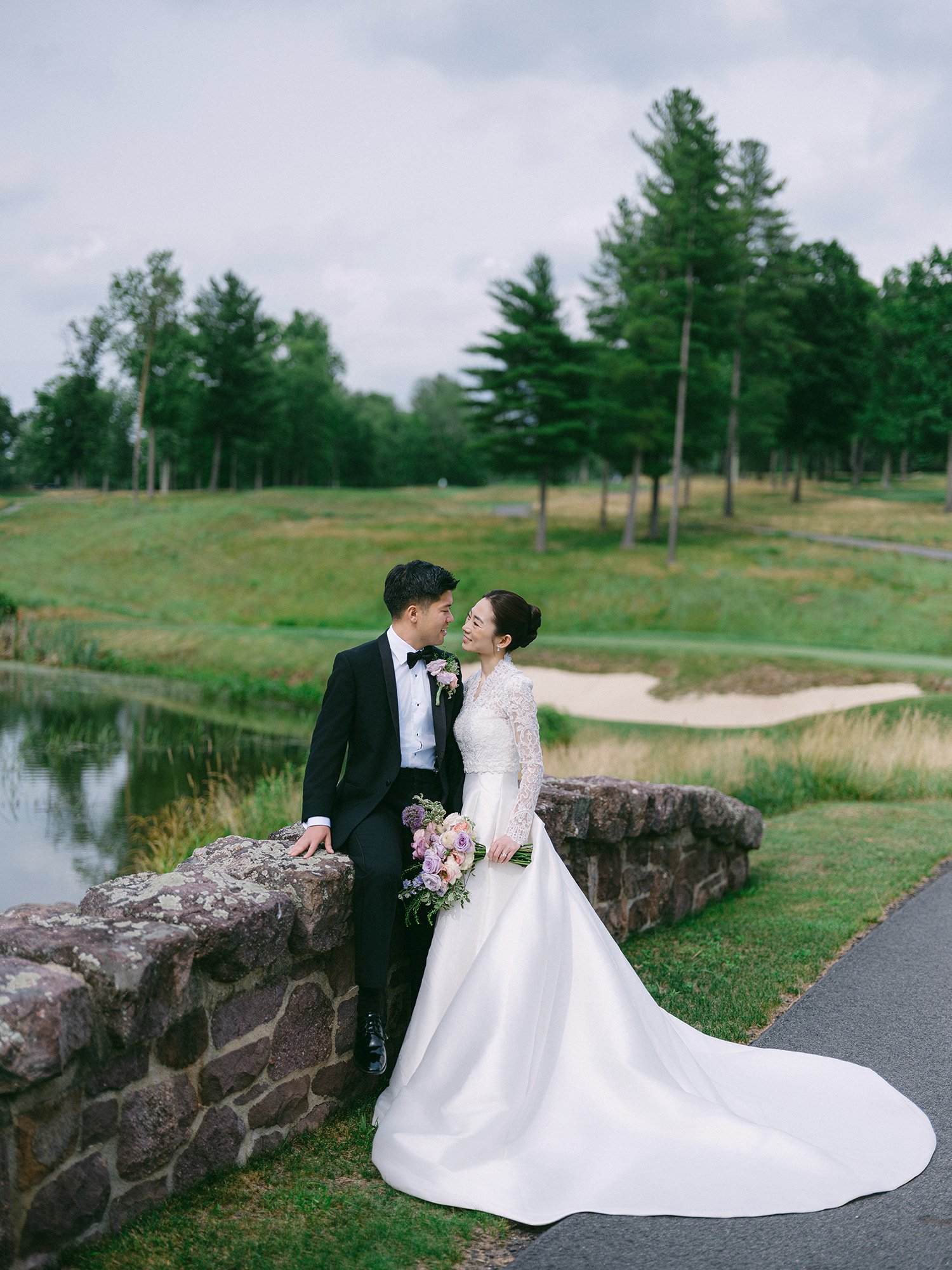 Wedding portrait of Amanda and Michael smiling in front of the historic mansion at Hamilton Farm Golf Club by Haseok Chung Studio.
