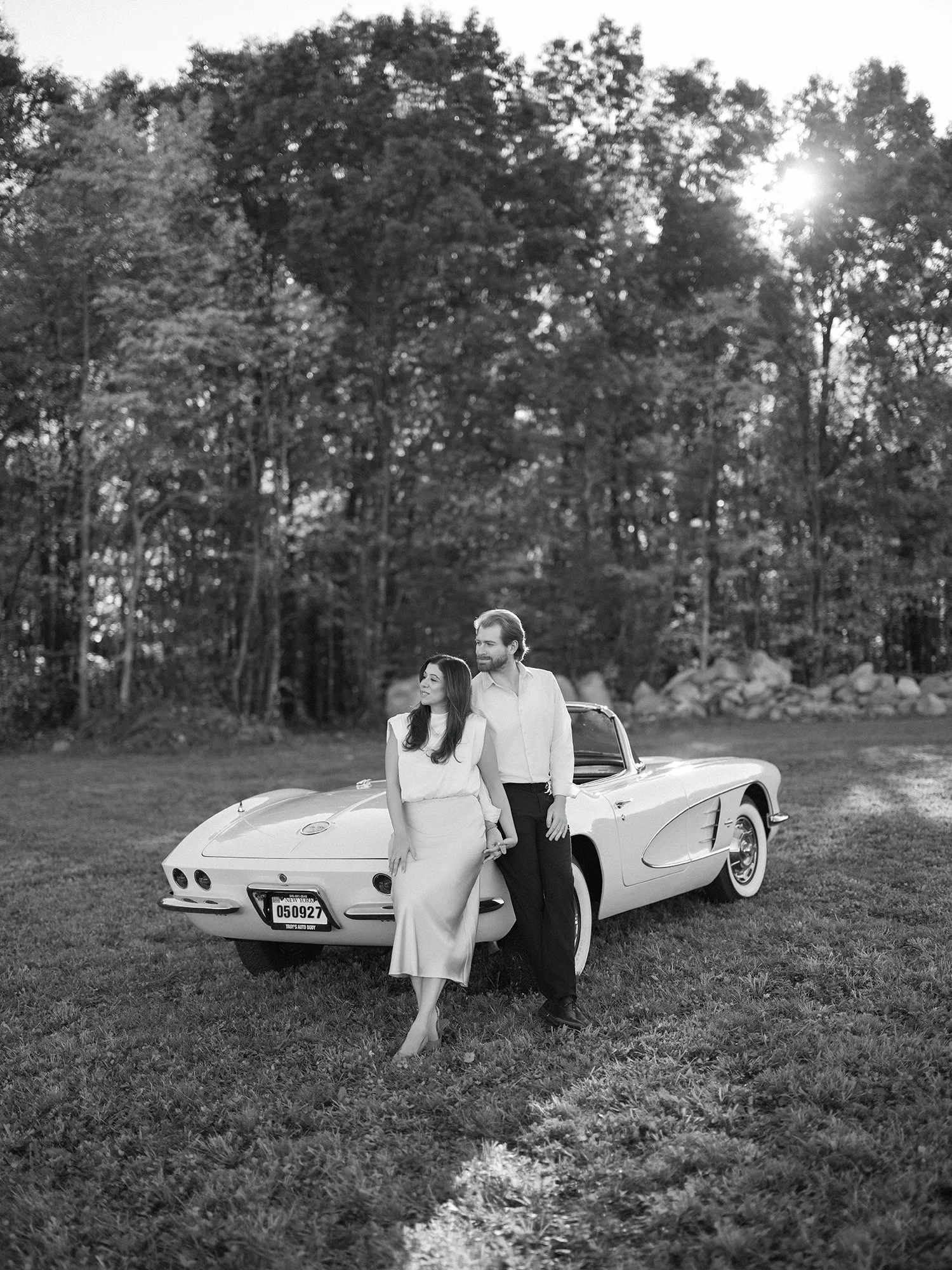 Daniel and Sandra beside a white 1960s Corvette convertible on a hill above the Hudson Valley
