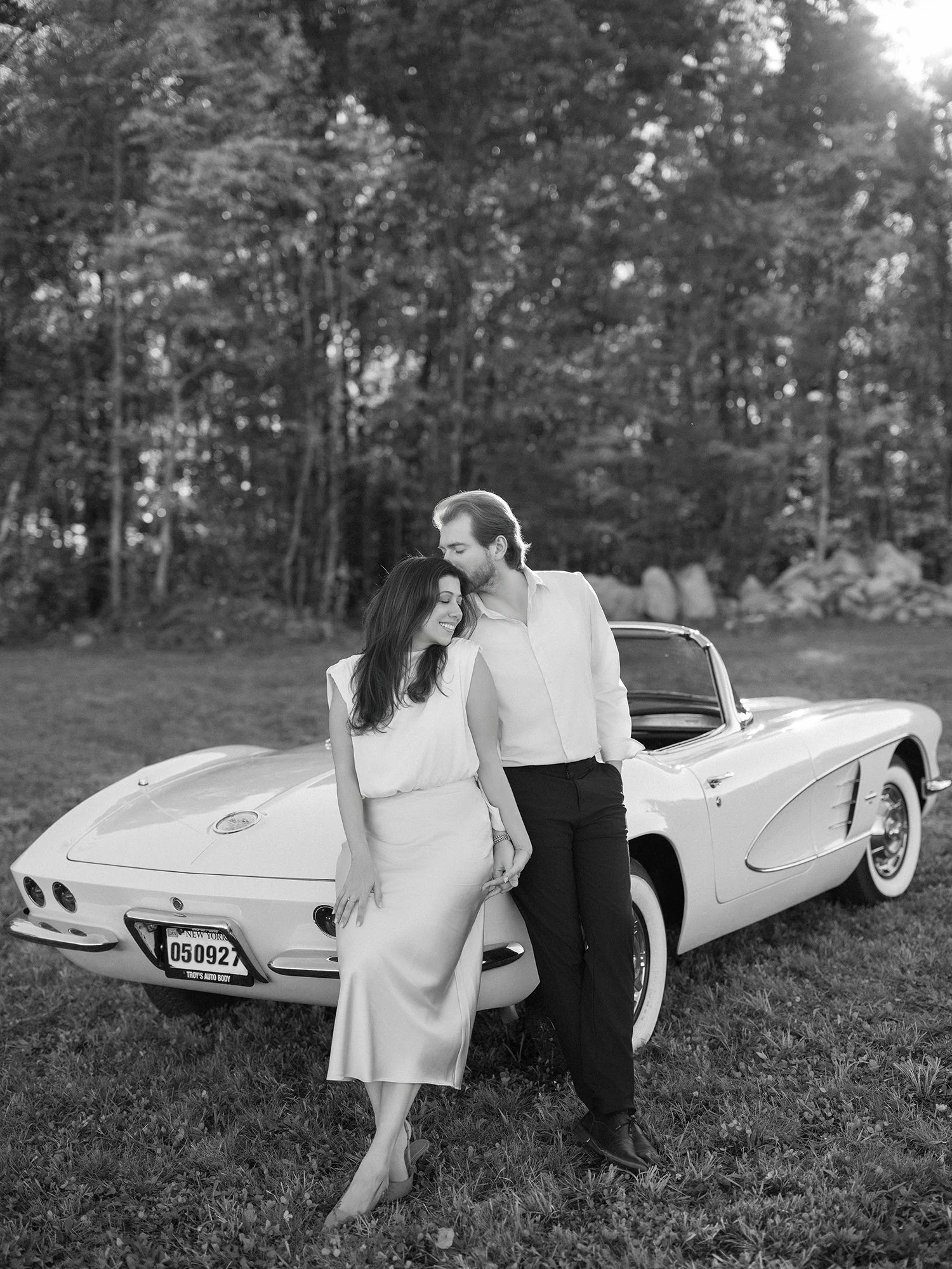 Daniel and Sandra beside a white 1960s Corvette convertible on a hill above the Hudson Valley