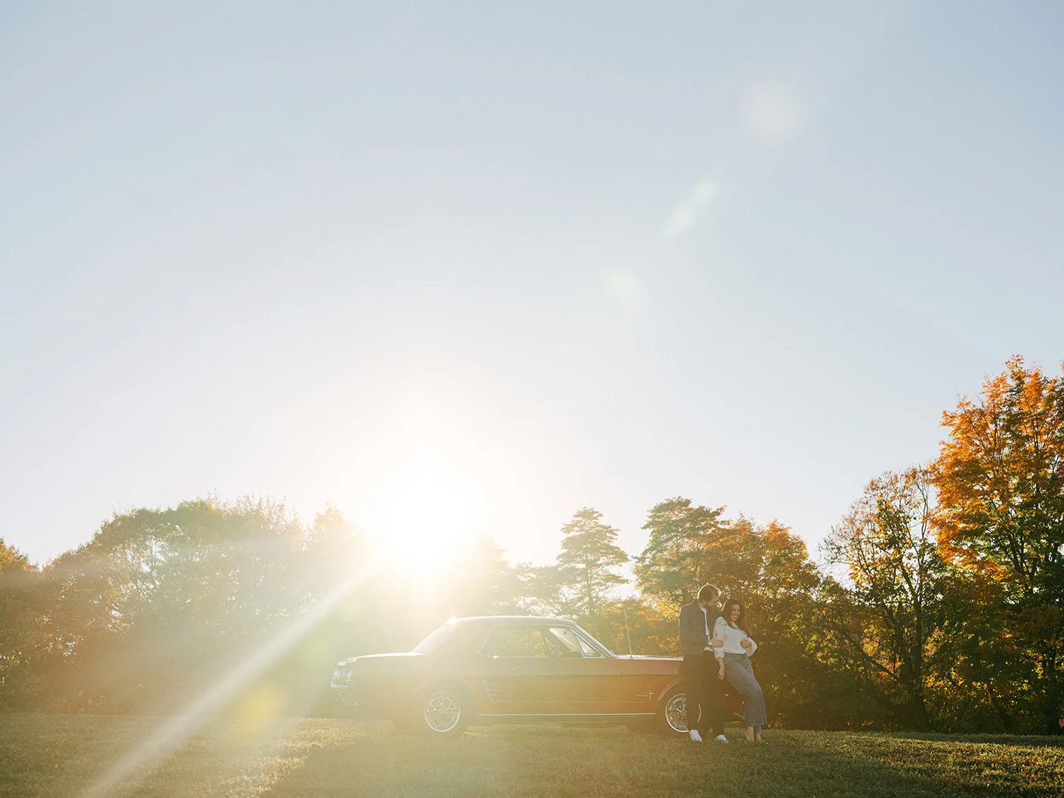 The couple with a red 1960s Ford Mustang at their engagement session in Milton, New York