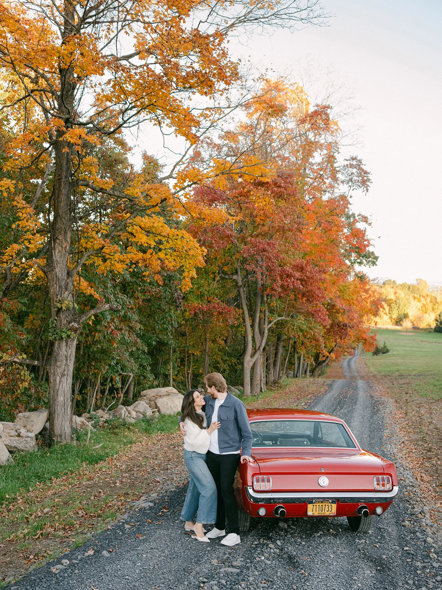 The couple with a red 1960s Ford Mustang at their engagement session in Milton, New York