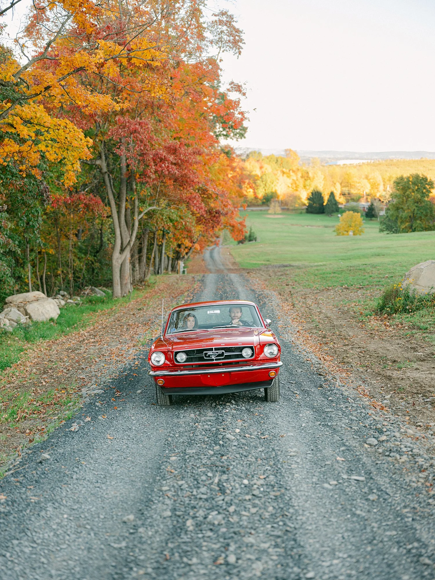 The couple with a red 1960s Ford Mustang at their engagement session in Milton, New York