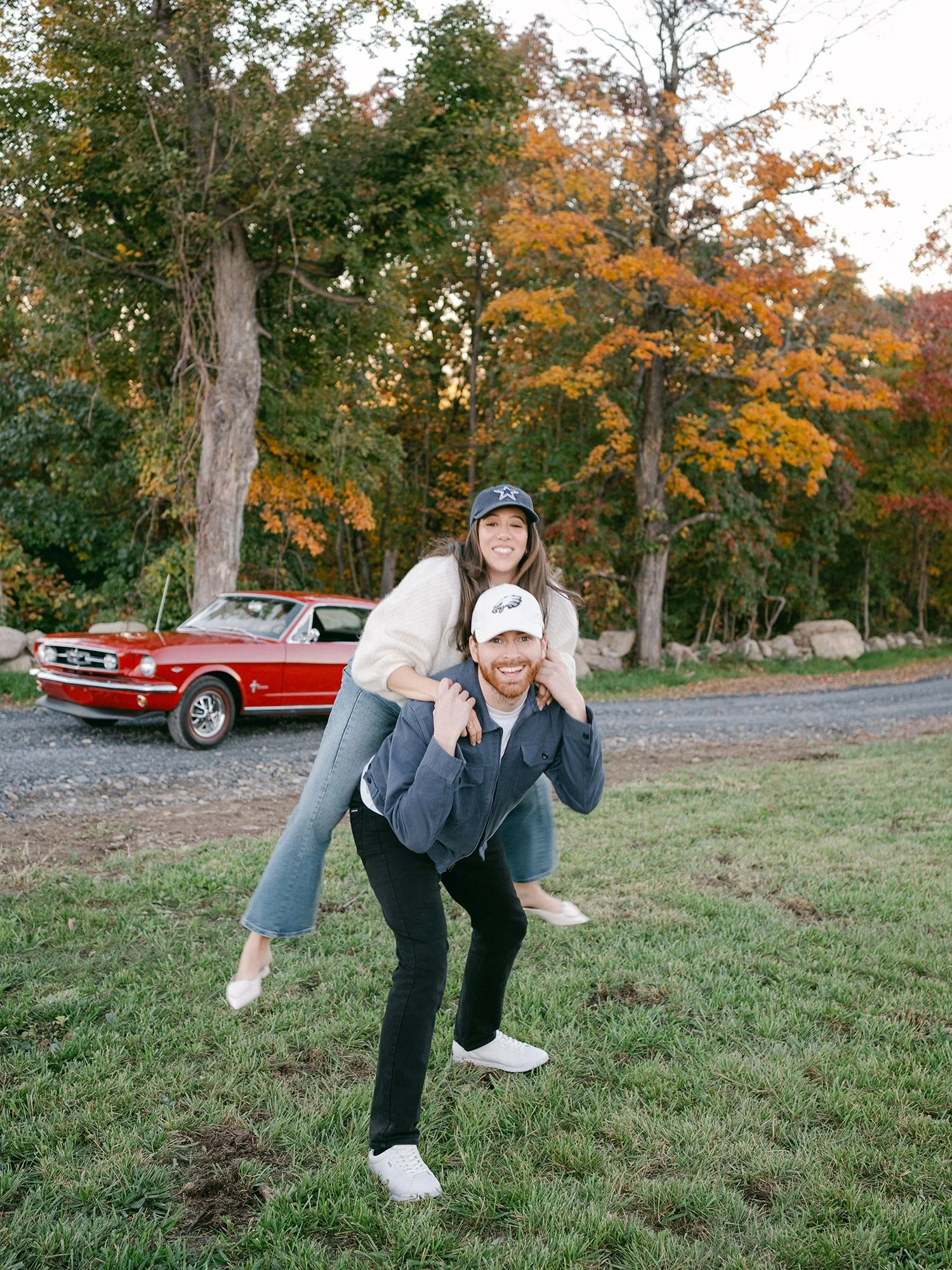 The couple with a red 1960s Ford Mustang at their engagement session in Milton, New York