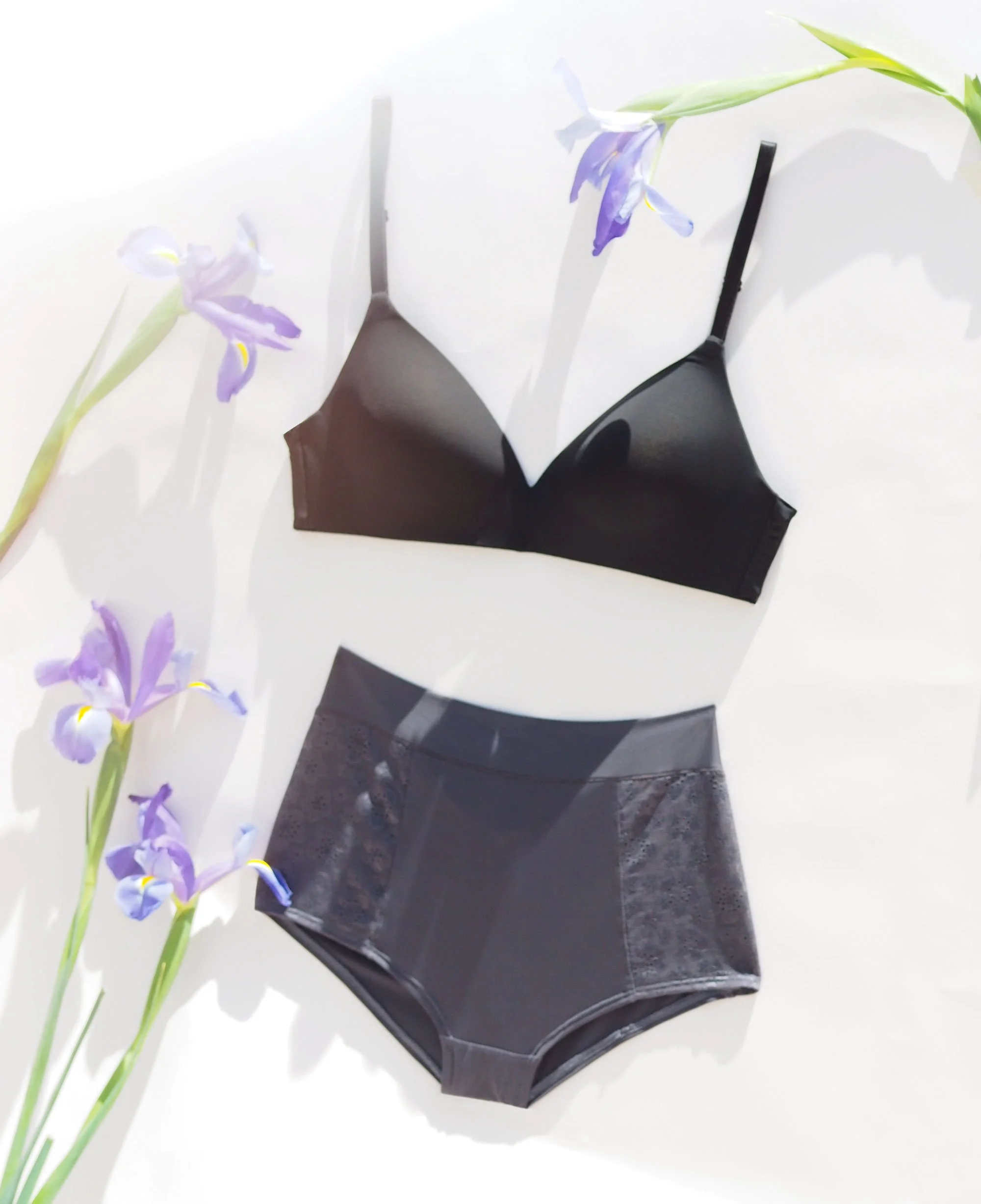 Black bra and high-waisted panties with purple flowers on white background.