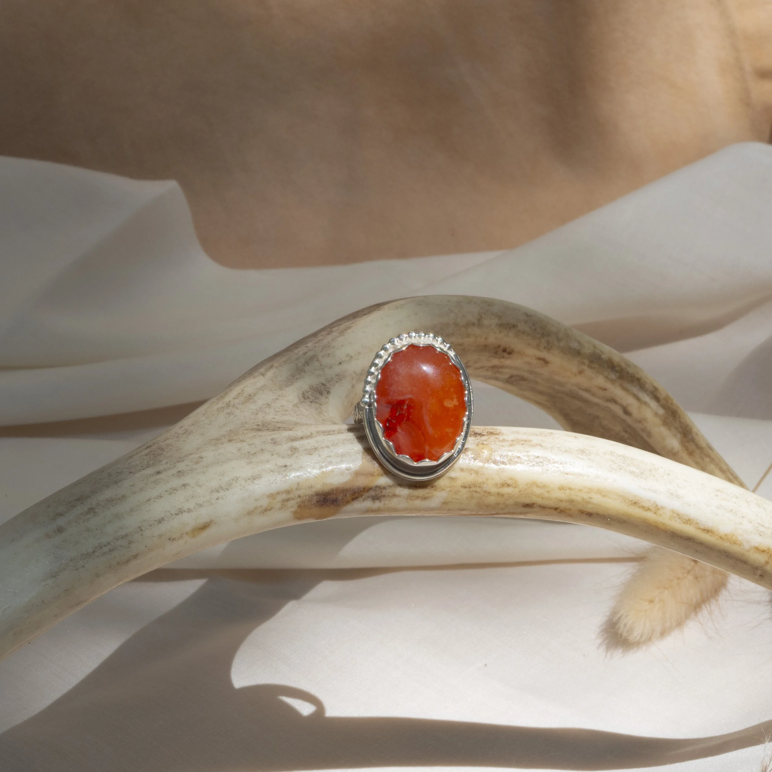 Orange gemstone ring with silver setting on antler
