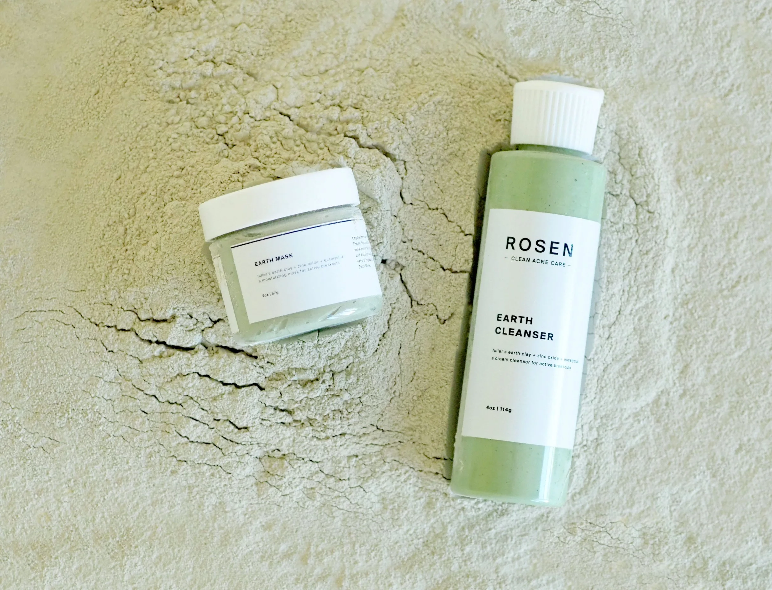 Earth Mask and Earth Cleanser bottles lying on a textured surface