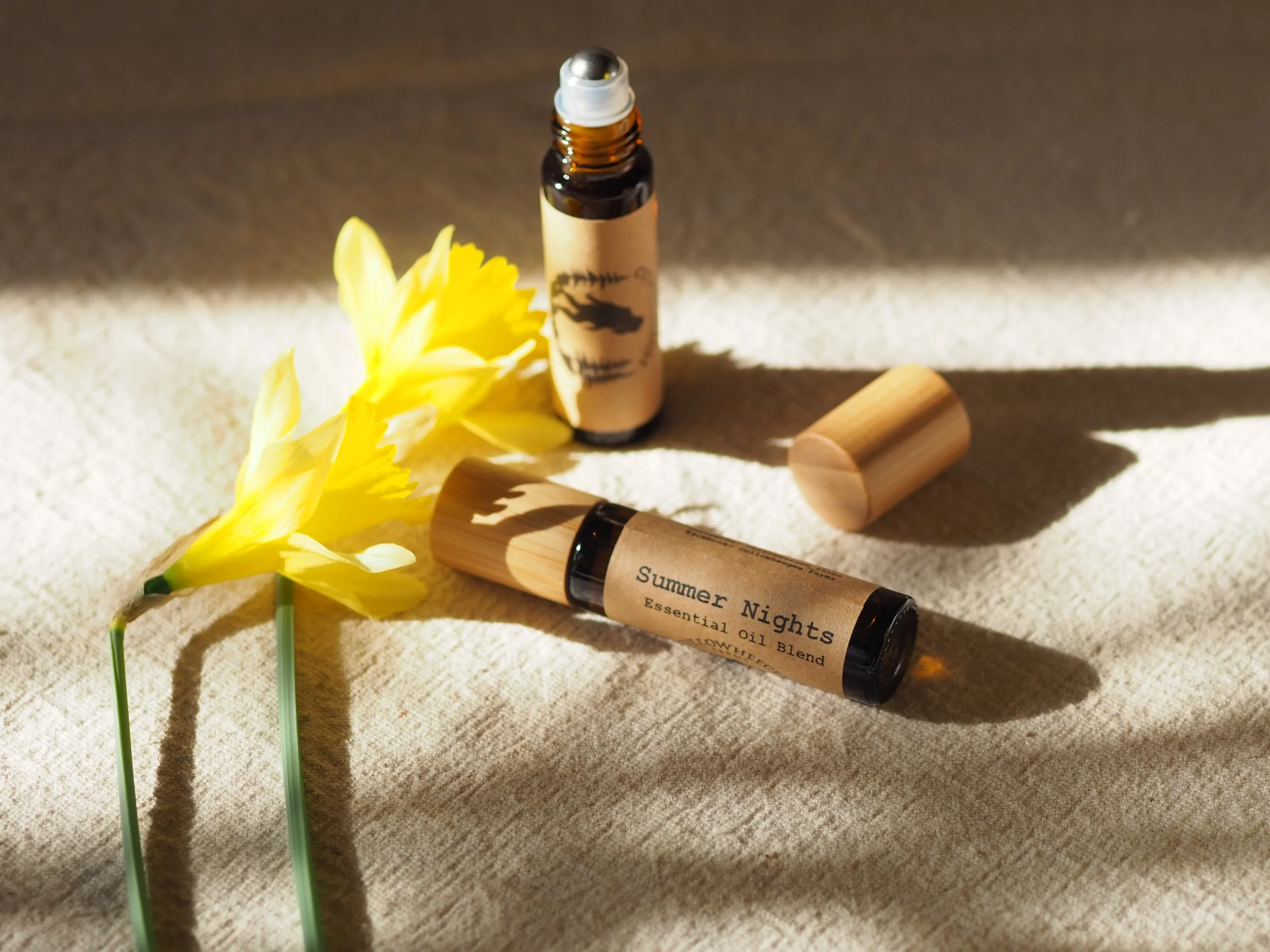 Essential oil bottles labeled "Summer Nights" with yellow flowers on a textured fabric background.