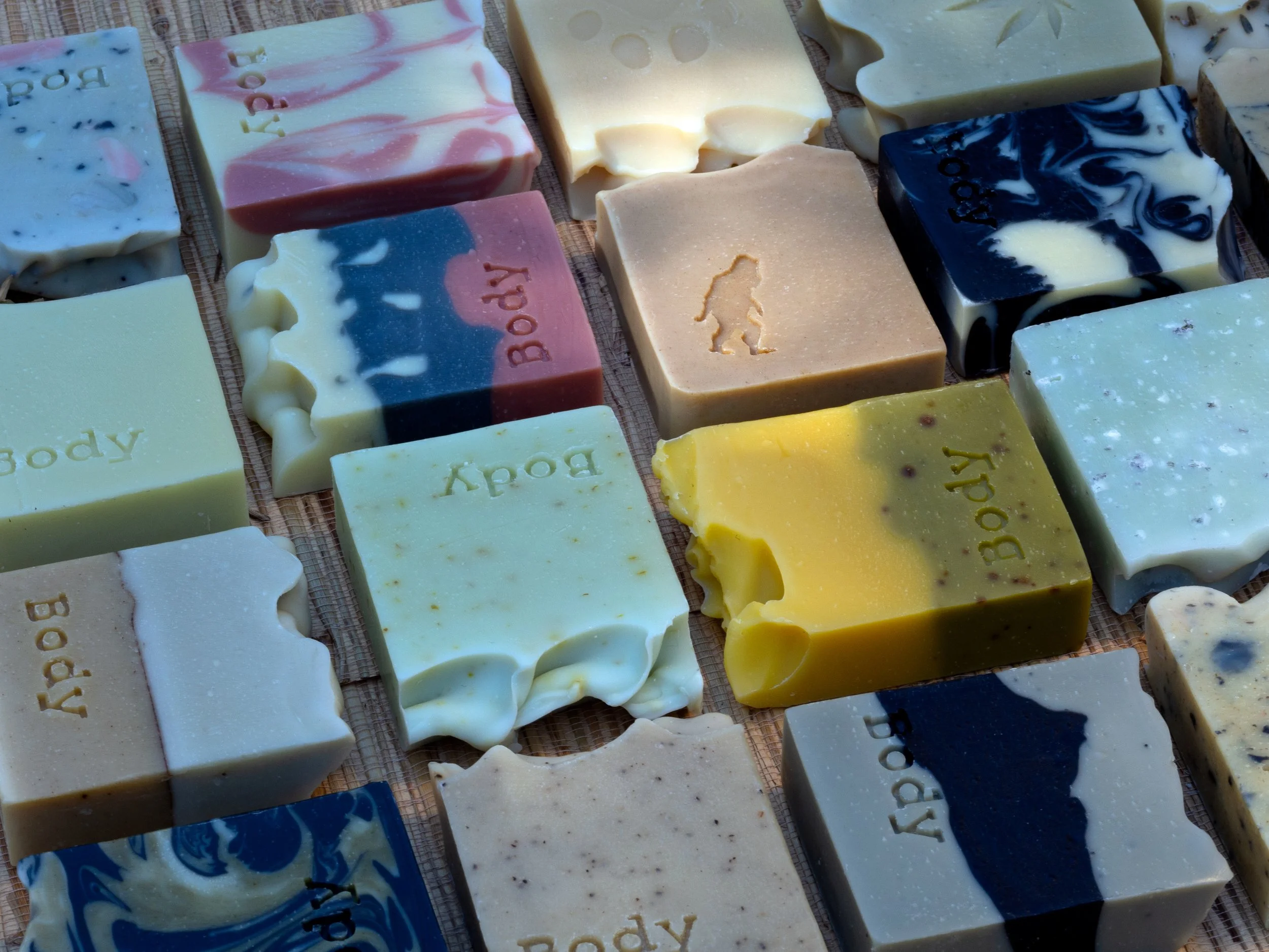 Variety of handmade soap bars with different colors and patterns arranged on a wooden surface.